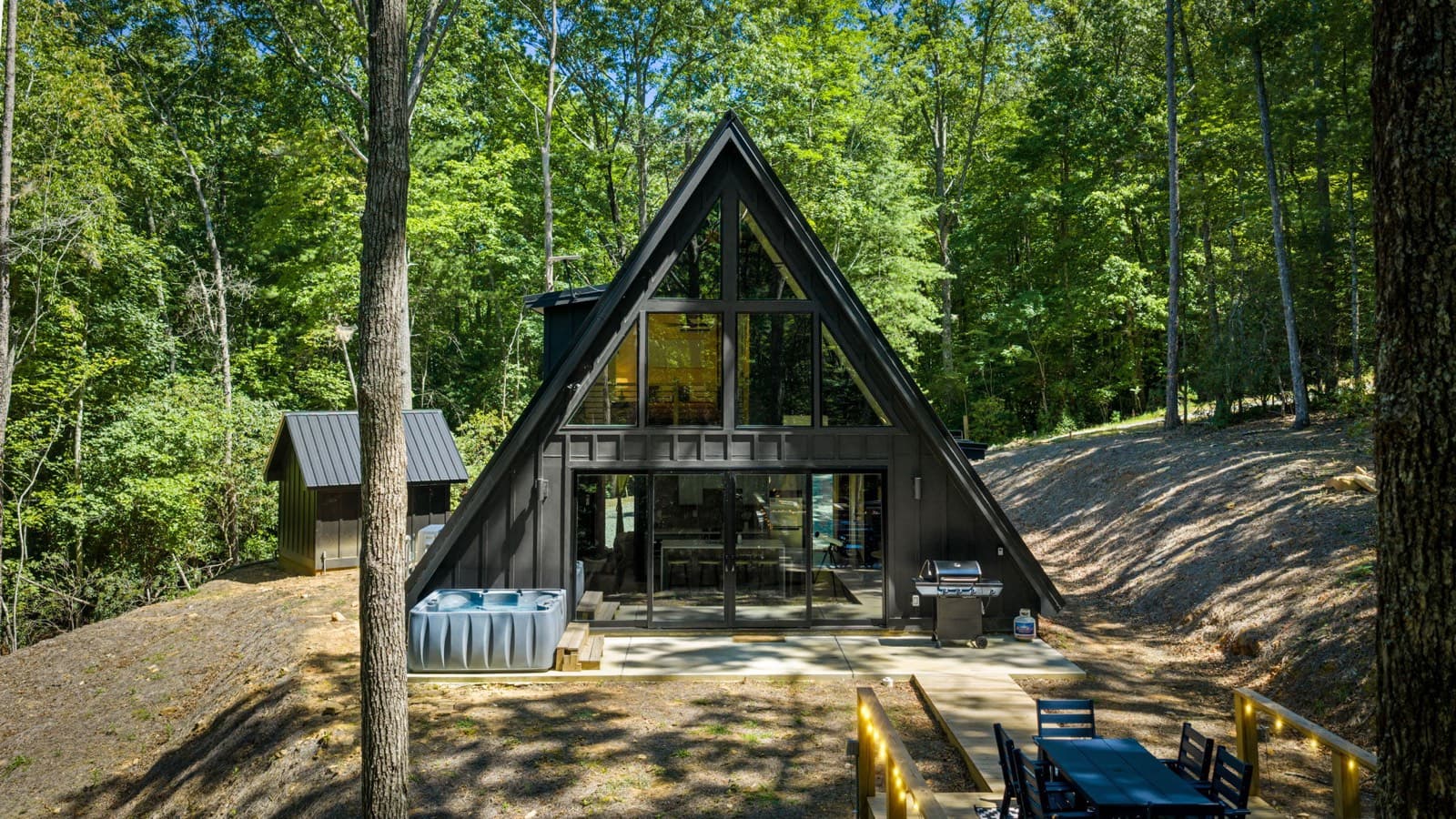Black Ember A-frame in summer with hot tub and outdoor dining